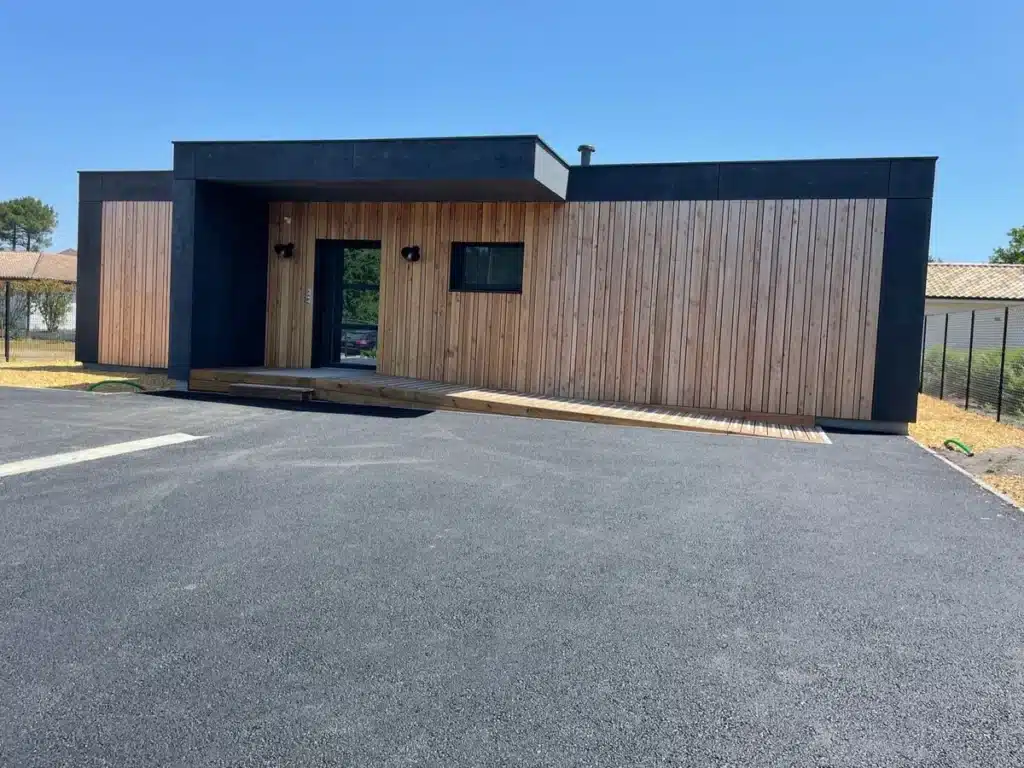 Maison contemporaine avec isolation thermique par l’extérieur et bardage bois naturel, associée à des finitions en panneaux noirs pour un design moderne et épuré.